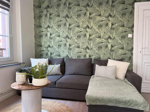 a living room with a couch and a green wall at Gîte Ripcup au coeur de Ribeauvillé in Ribeauvillé