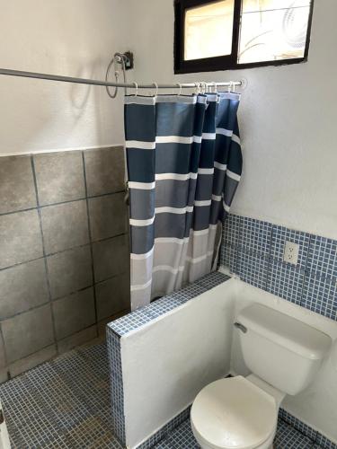 a bathroom with a toilet and a shower curtain at Pura Vida Hostel in Tamarindo