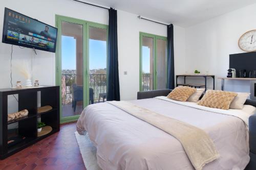 une chambre avec un grand lit avec une télévision à écran plat dans l'établissement Le Cali, Terrase, Parking, Piscine, Clim, à Villeneuve-Loubet