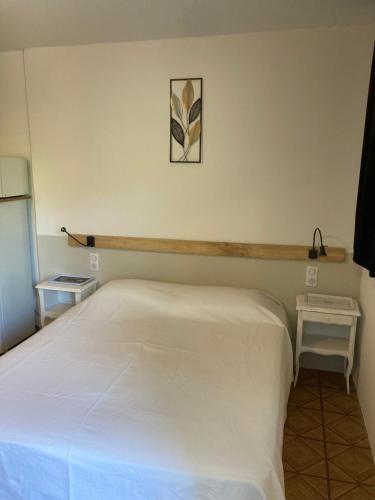 - une chambre avec un lit blanc et une photo sur le mur dans l'établissement Studio idéal cure thermale, à Gréoux-les-Bains
