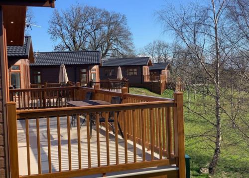 a large wooden deck with a house in the background at Badgers Retreat Holiday Park in Hunton