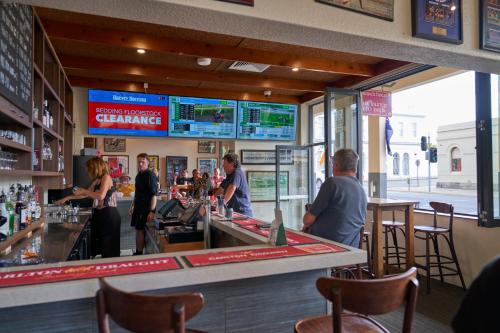 a group of people standing at a bar in a restaurant at Shamrock Hotel Kyneton in Kyneton