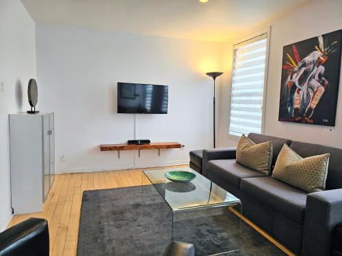a living room with a couch and a tv at Espace William by Hébergements DCL in Quebec City