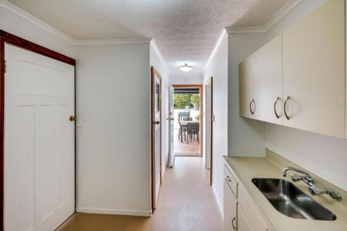 a kitchen with a sink and a door to a dining room at Napier Hilltop Stays - Views, Pool & Pet Friendly! in Napier