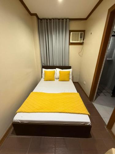 a bed with two yellow pillows in a small room at Subic Bay Baloy Long Beach Hotel in Olongapo