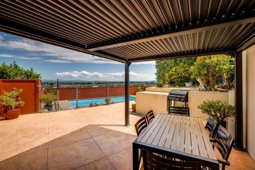 a patio with a wooden table and a grill at Napier Hilltop Stays - Views, Pool & Pet Friendly! in Napier