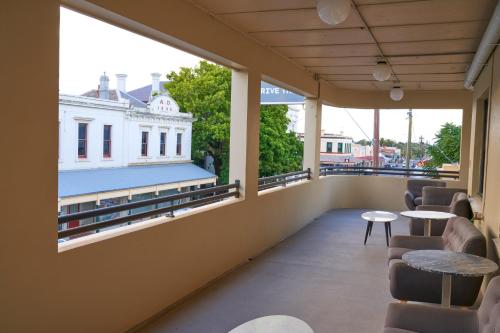 a balcony with tables and chairs and windows at Shamrock Hotel Kyneton in Kyneton