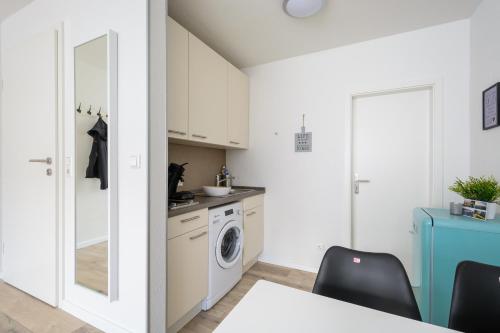 a kitchen with white cabinets and a washing machine at Deluxe Appartements am Münster in Freiburg im Breisgau