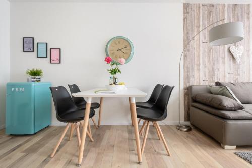 a living room with a table and chairs and a clock at Deluxe Appartements am Münster in Freiburg im Breisgau