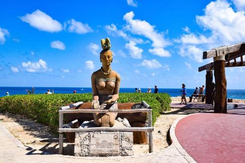 Eine Statue einer Frau auf einer Bank am Strand. in der Unterkunft casa brisa marina in Isla Mujeres