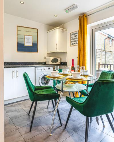 a kitchen with a table and green chairs at The Shropshire - Sleeps 8 - Coventry, Groups, 100GB WiFi, Luxury, Parking in Parkside