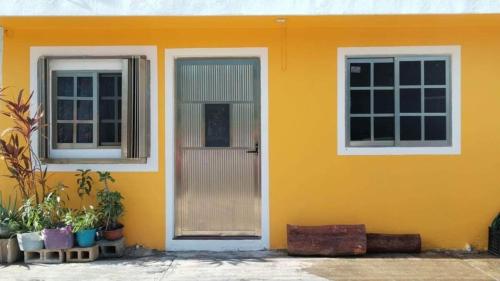 ein gelbes Haus mit einer Tür und zwei Fenstern in der Unterkunft casa brisa marina in Isla Mujeres