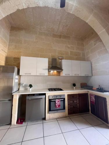a kitchen with white cabinets and a stove top oven at Arkati house in Munxar