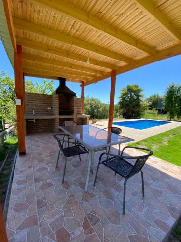 a patio with a table and chairs under a wooden roof at CASA A11 Lago Rapel in El Estero