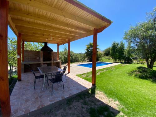 a patio with a table and chairs under a wooden pergola at CASA A11 Lago Rapel in El Estero