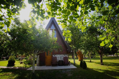 a small log cabin with two chairs in a yard at Ethno Village Štitarica in Mojkovac