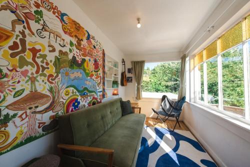 a living room with a couch and a colorful wall at Sunrays Stay - Stylish Retreat in New Plymouth