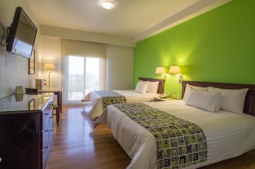 una habitación de hotel con 2 camas y una pared verde en HG Hotel, en Guadalajara