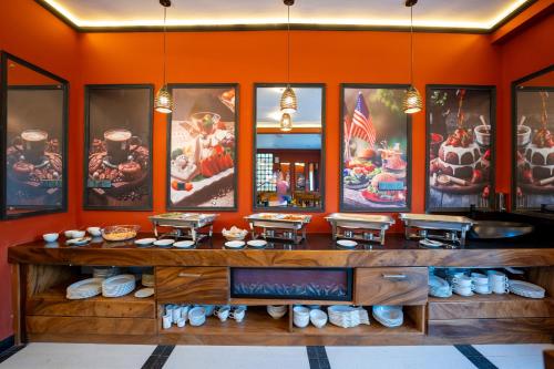 a restaurant with an orange wall with pictures at London Eye Hotel Nuwaraeliya in Nuwara Eliya