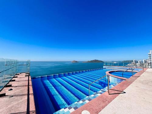 a swimming pool with the ocean in the background at Vista a la ciudad sobre el malecón by G P S rentas in Mazatlán