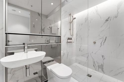 a white bathroom with a sink and a toilet at Luxury 2BR 2BA & Free Parking - 5 Min Walk to Town Hall & Darling Harbour in Sydney