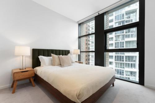 a bedroom with a large bed and large windows at Luxury 2BR 2BA & Free Parking - 5 Min Walk to Town Hall & Darling Harbour in Sydney