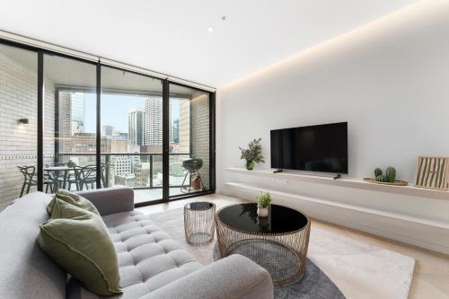 a living room with a couch and a tv at Luxury 2BR 2BA & Free Parking - 5 Min Walk to Town Hall & Darling Harbour in Sydney