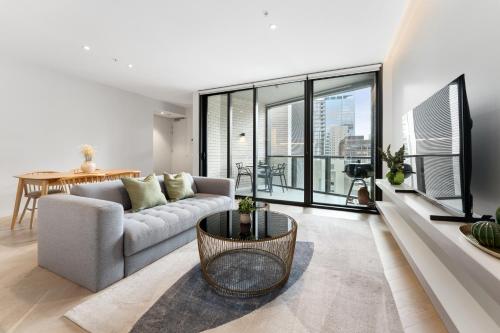 a living room with a couch and a table at Luxury 2BR 2BA & Free Parking - 5 Min Walk to Town Hall & Darling Harbour in Sydney