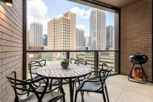 a table and chairs on a balcony with a view of the city at Luxury 2BR 2BA & Free Parking - 5 Min Walk to Town Hall & Darling Harbour in Sydney