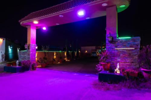 - une terrasse avec des lumières violettes dans une maison la nuit dans l'établissement شاليهات بالي, à Jilhayah