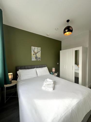 a large white bed in a bedroom with a green wall at Abbey Apartments in Dublin
