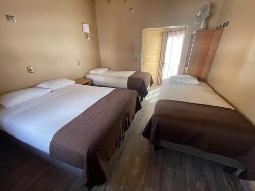 a hotel room with two beds and a window at Hotel La Cochera in San Pedro de Atacama