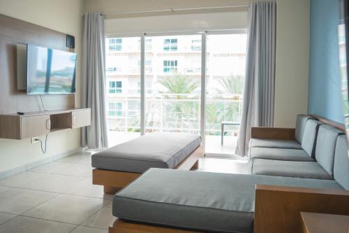 a hotel room with two beds and a flat screen tv at condominio con una bonita vista del puerto deportivo de G P S rentas in Mazatlán