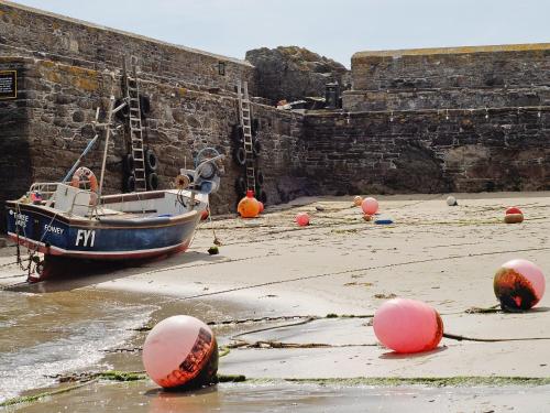 a boat sitting on the beach next to a wall at The Gables in Gorran Haven