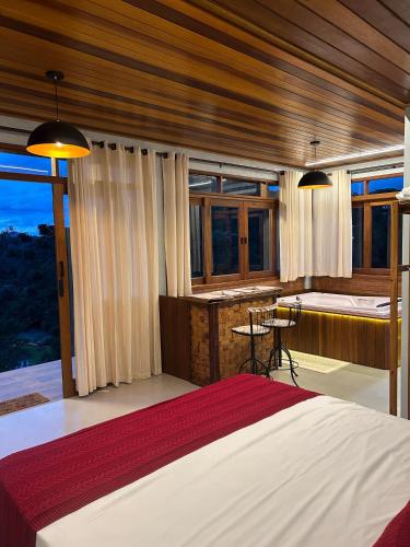 a bedroom with a bed and a desk and windows at Chalés Amantes da Montanha - Visconde de Mauá in Bocaina de Minas