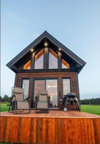 two chairs and a house with windows on a deck at Chalets Nautika in Gaspé