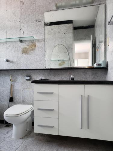 a white bathroom with a toilet and a mirror at Cobertura Duplex Próx da Praia in Recife
