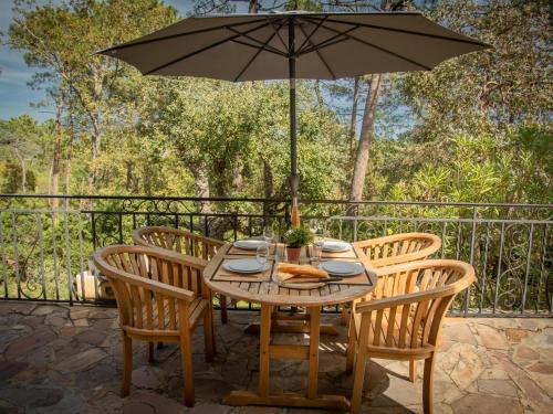 une table et des chaises avec un parasol sur une terrasse dans l'établissement Le Capitou, à Fréjus