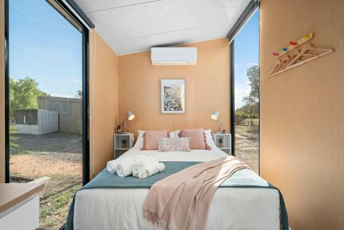 Un dormitorio con una cama y una ventana grande. en Banyena Homestead by Tiny Away, en Banyena