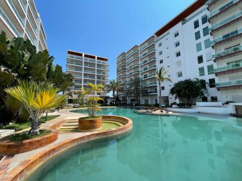 a large swimming pool with palm trees and buildings at penthouse vista a 5min de la playa by G P S rentas in Mazatlán