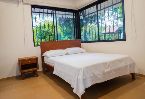 a bedroom with a bed and two windows at Cabaña Campestre Villa Valeria in Yopal