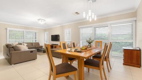 a dining room and living room with a table and chairs at Fairway & Vines in Pokolbin