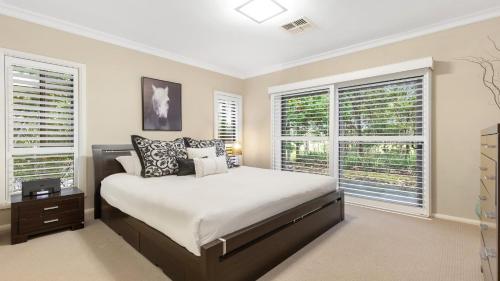 a bedroom with a large bed and two windows at Fairway & Vines in Pokolbin
