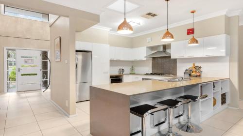 a kitchen with white cabinets and a large island at Fairway & Vines in Pokolbin