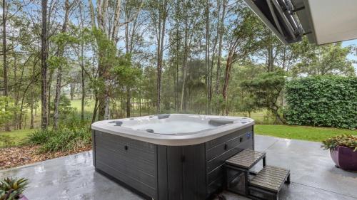 a jacuzzi tub on a patio with trees at Fairway & Vines in Pokolbin
