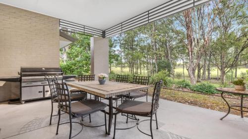 a patio with a table and chairs and a grill at Fairway & Vines in Pokolbin