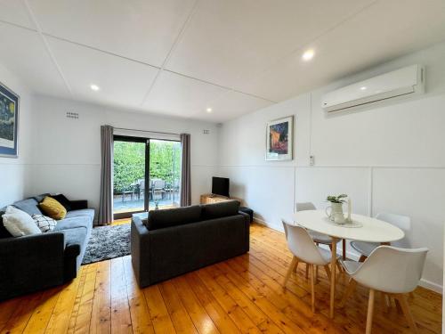 a living room with a couch and a table at Three-Bedroom Stylish & Cosy Retreat with Courtyard, Near Geelong in Norlane