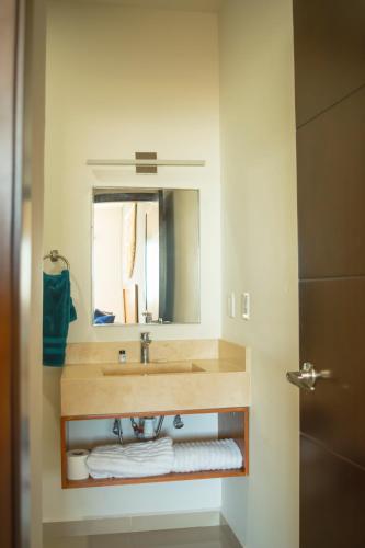 a bathroom with a sink with a mirror and towels at Cómodo con piscina y cerca de la playa by G P S rentas in Mazatlán