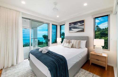 ein Schlafzimmer mit großem Bett und großen Fenstern in der Unterkunft CoralAir Whitsundays in Airlie Beach