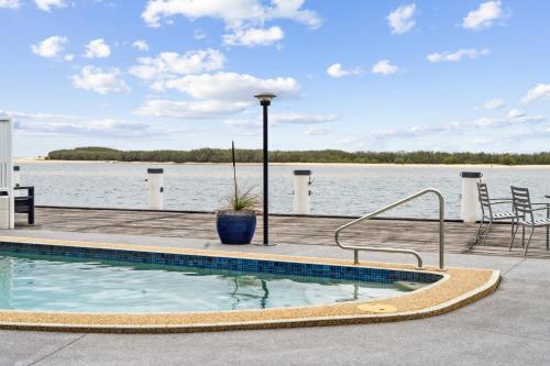 a swimming pool next to a body of water at Pumicestone Passage Waterfront Escape in Caloundra